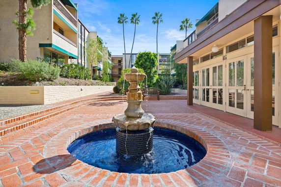 Front view of a multi-story residential building with a courtyard and water fountain.