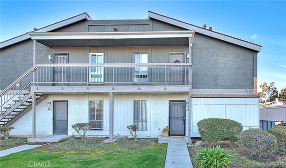 Front view of a two-story residential building with an exterior staircase and balcony.