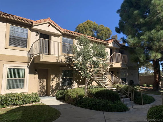 Front view of a two-story residential building with outdoor staircases and a walkway.