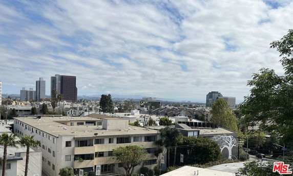 Panoramic view of buildings in a cityscape under a cloudy sky.