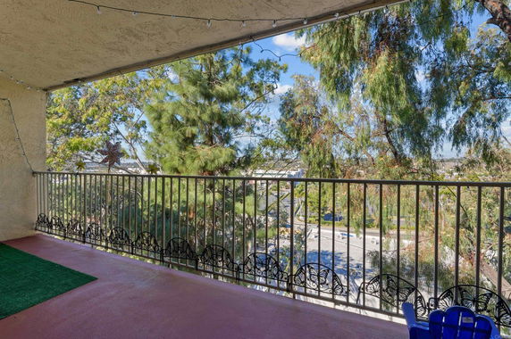 A balcony with a view of trees and surrounding areas beyond the railing.