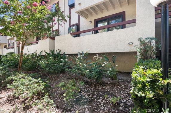 Front view of a multi-story building with balconies and a landscaped garden.