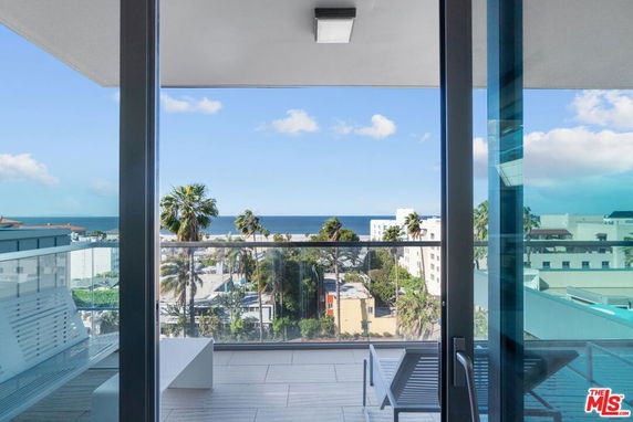 View from a balcony with a wide view of the ocean and surrounding buildings.