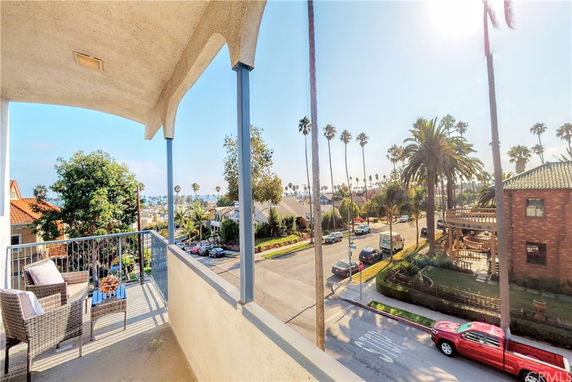 Elevated view from a balcony overlooking a street lined with palm trees and residential houses.