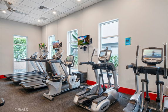 Indoor gym area with exercise equipment and televisions.