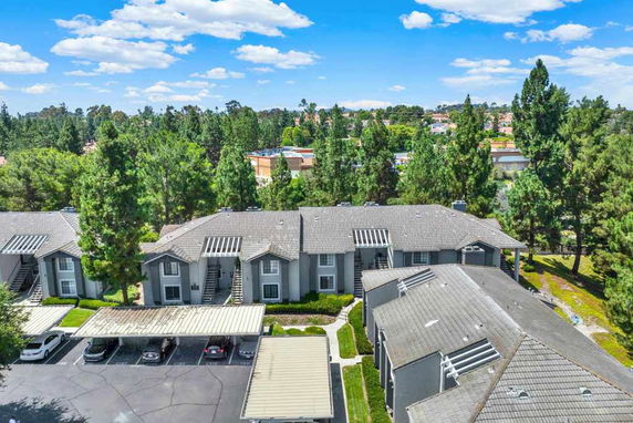 Aerial view of a residential complex with multiple buildings surrounded by trees.