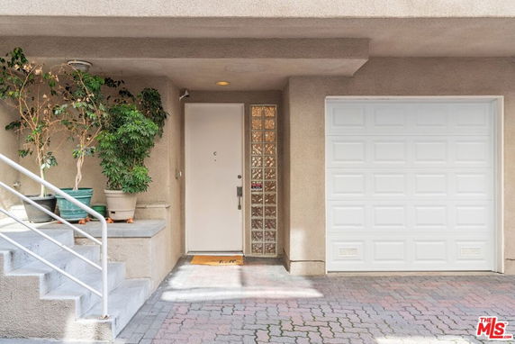 Front view of a building entrance with stairs and a garage door.