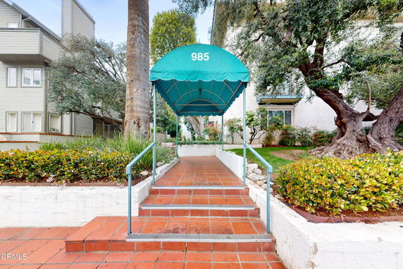 Front view of a building entrance with a green awning covering the walkway.