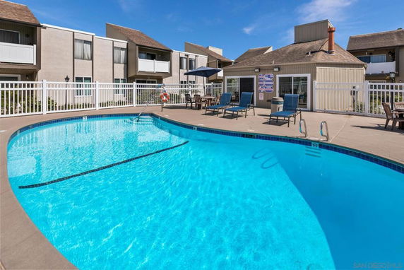Outdoor swimming pool area with lounge chairs and surrounding building structure.