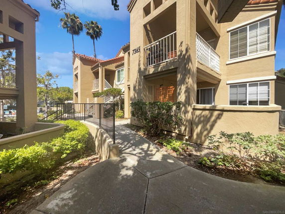 Front view of a multi-story building with balconies and a walkway.