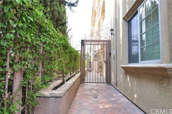 Side entrance of a building with a decorative metal gate and tiled pathway.