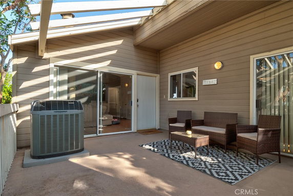 Outdoor rooftop patio with seating and an air conditioning unit.