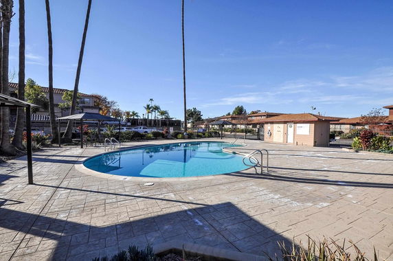 Outdoor swimming pool area with surrounding pavements and buildings in the background.