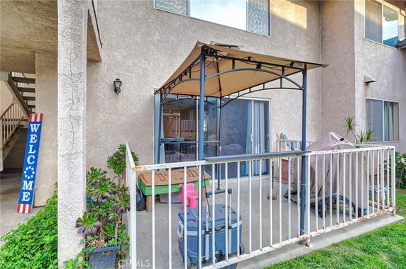 Patio view of a two-story residential building with sliding doors and awning.