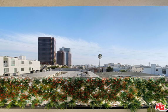 Panoramic view from a building balcony showing surrounding city buildings and skyline.