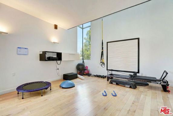 Indoor gym area with exercise equipment including a trampoline, rowing machine, and free weights.