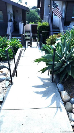 Pathway leading to residential buildings with a flag and plants.