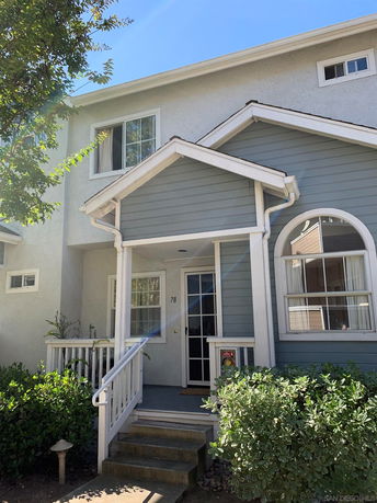 Front view of a two-story house with a small porch and staircase.