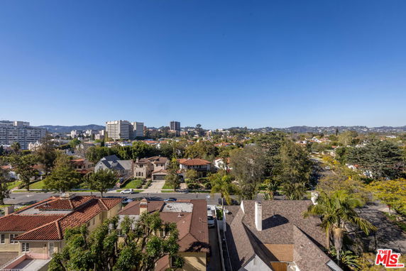 Panoramic view of a suburban neighborhood with houses, trees, and distant city buildings.
