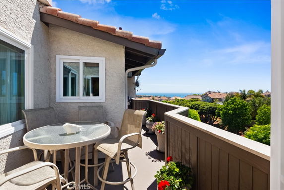 Balcony with outdoor seating offering a wide view of the surrounding area and ocean.