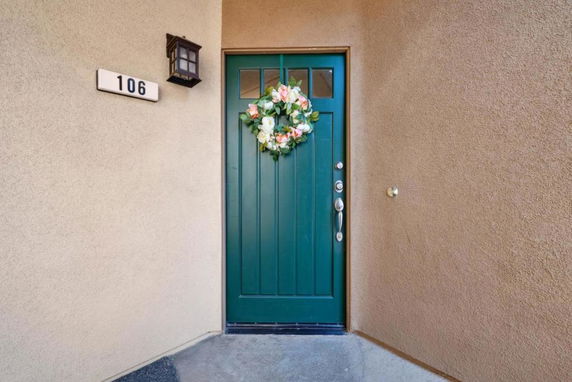 Front view of a house entrance with a green door and a floral wreath.