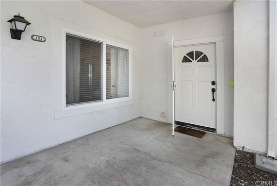 Entryway of a house with a white front door and adjacent window.