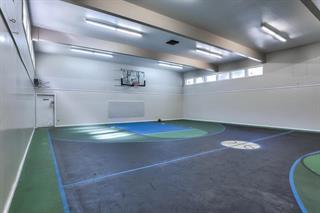 Indoor gymnasium with a basketball hoop and court markings.