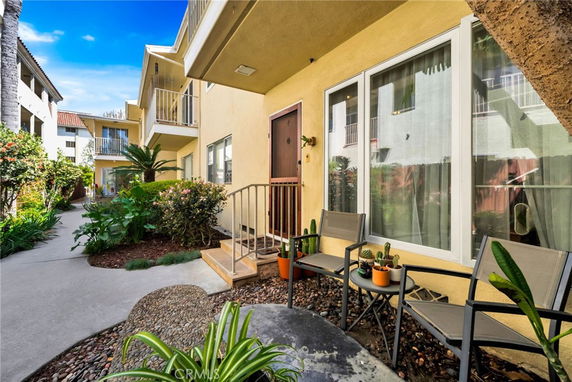 Front view of a multi-story apartment building with a small outdoor seating area.