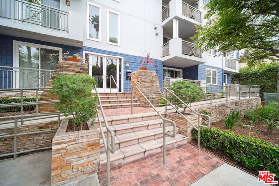 Front view of a modern multi-story building with stone accents and balconies.