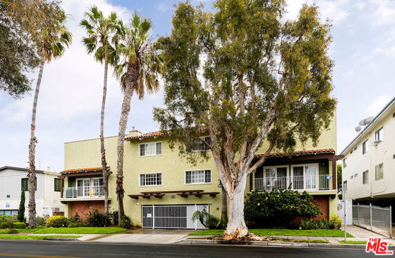 Front view of a multi-story building with balconies and gated entrance.