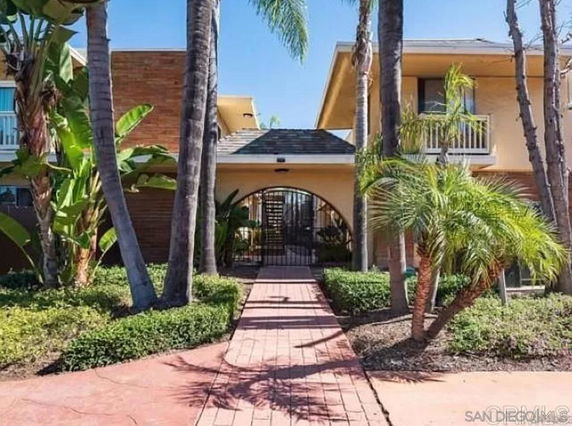 Front view of a building with palm trees and an arched entryway.