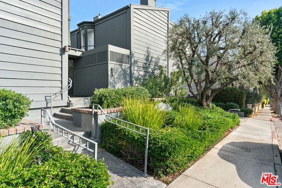 Front view of a modern multi-story building with gray siding and steps leading to the entrance.