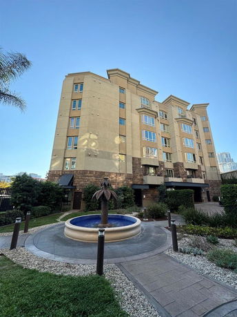 Front view of a multi-story residential building with large windows and a decorative fountain in front.