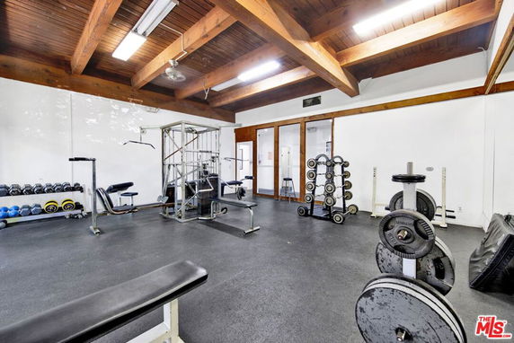 Indoor gym area with various exercise equipment and wooden ceiling beams.