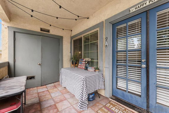 Outdoor entrance area with a table covered by a checkered cloth and decorative items.