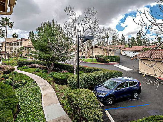 View of residential area with pathways, parking, and lush greenery.