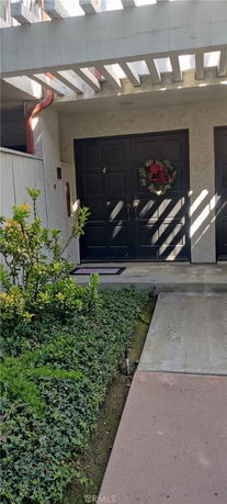 Front view of a residential unit entrance with a black double door and decorative wreath.