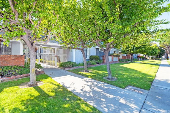 Front view of a residential building with gated entrance and surrounding trees.