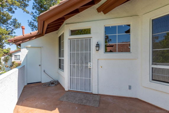 Rooftop area with a door leading into a house, windows, and railing.