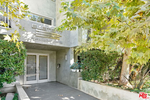 Front view of a building entrance with glass doors and surrounding trees.