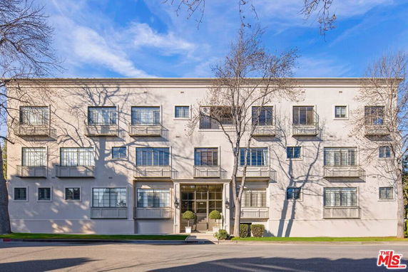 Front view of a multi-story apartment building with multiple windows and balconies.