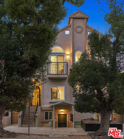 Front view of a multi-story house with a balcony and arched windows.