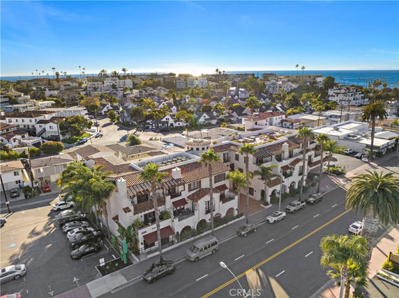 Aerial view of a residential area near the coast with multi-story buildings and palm trees.