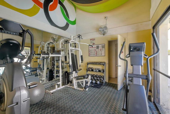 Indoor gym area with exercise equipment and mirrors on the wall.