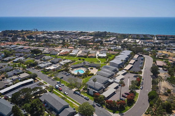 Panoramic view of a residential area with a swimming pool and the ocean in the background.