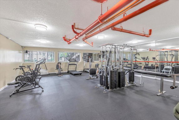Interior view of a gym with exercise equipment and mirrors.