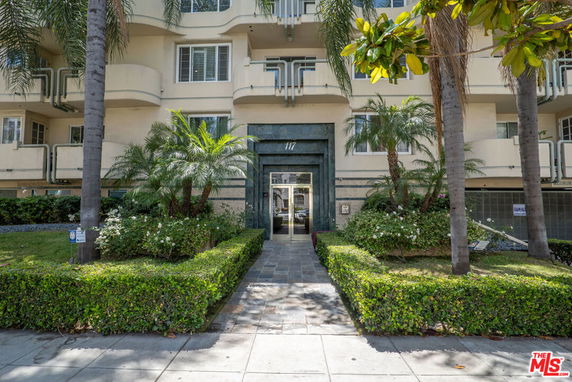 Front view of a multi-story apartment building with a landscaped entrance.