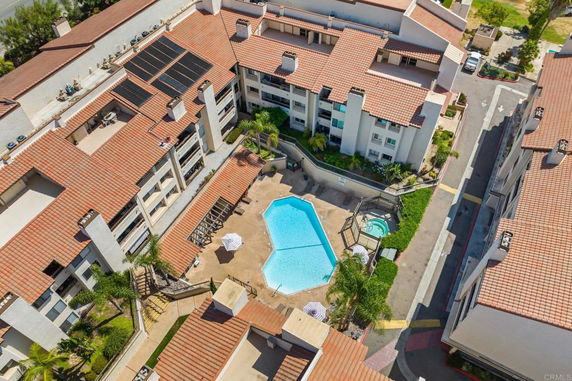 Aerial view of a multi-story building complex with a swimming pool and spa area in the center courtyard.