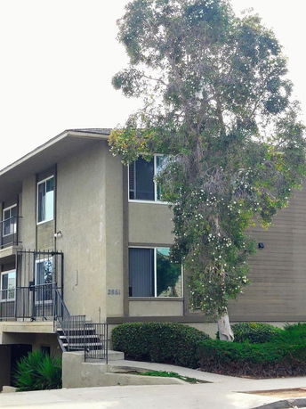 Front view of a two-story building with stairs and a covered porch entrance.