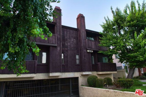 Front view of a two-story building with textured dark wood paneling and a gated entrance.